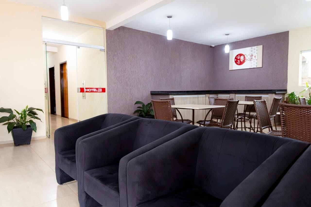 Un hall d’hôtel comprenant un comptoir d’accueil, un espace salon et une horloge fixée au mur.