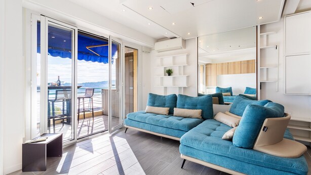 Una sala de estar moderna con un sofá azul, una mesita y un balcón con vistas.