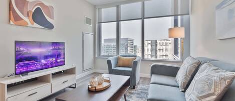 A modern living room with a large TV, a sofa, a chair, and a coffee table.