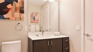 A modern bathroom with a toilet, sink, and dark wooden cabinet. - Luxury Apt In Heart of Seaport (Boston MA)