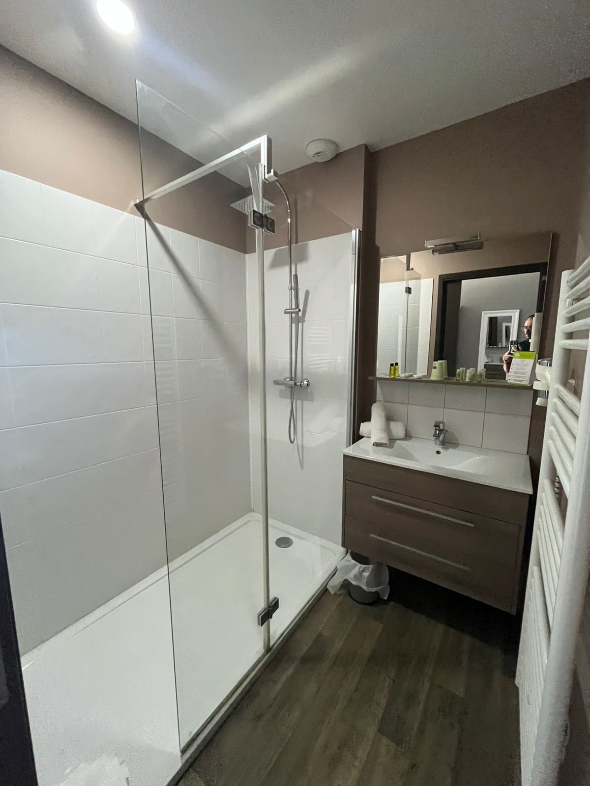 Un baño moderno con ducha de vidrio, tocador con espejo y inodoro.