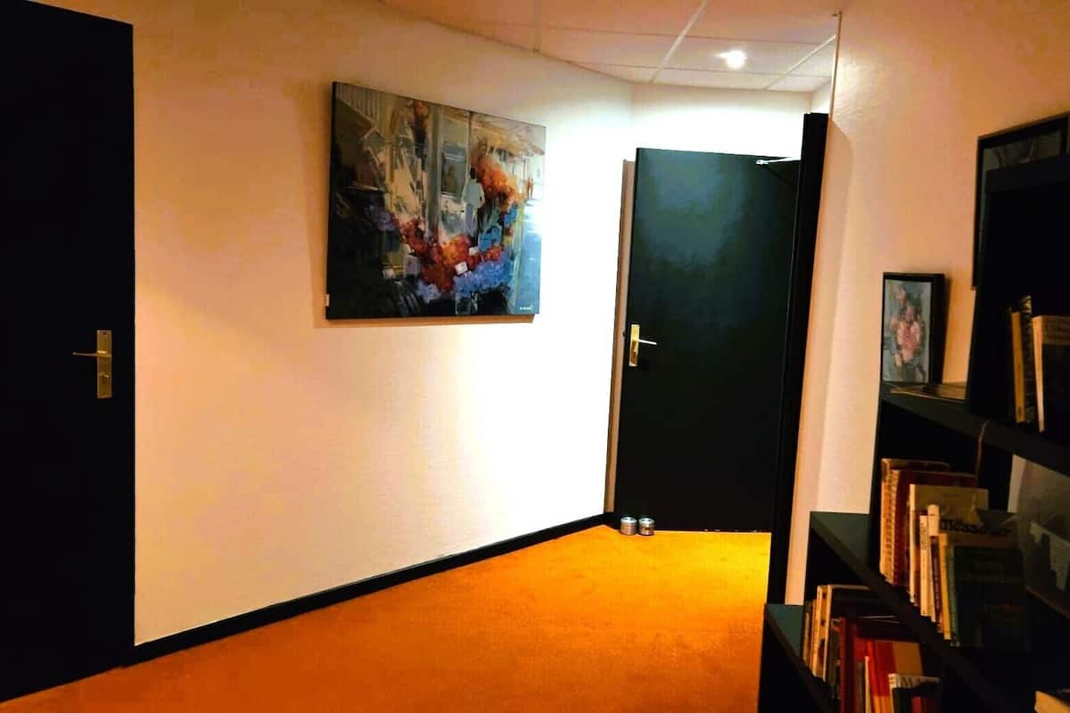 Un pasillo con una puerta, un cuadro en la pared y una estantería.