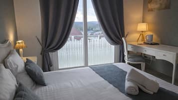 Une chambre d’hôtel avec un lit, un bureau, une chaise, une lampe et une vue sur une étendue d’eau par la fenêtre.