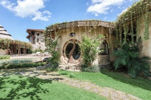A courtyard with a pool, a building with arches, and lush greenery. - Nuanu Suites & Accommodations (Tabanan)