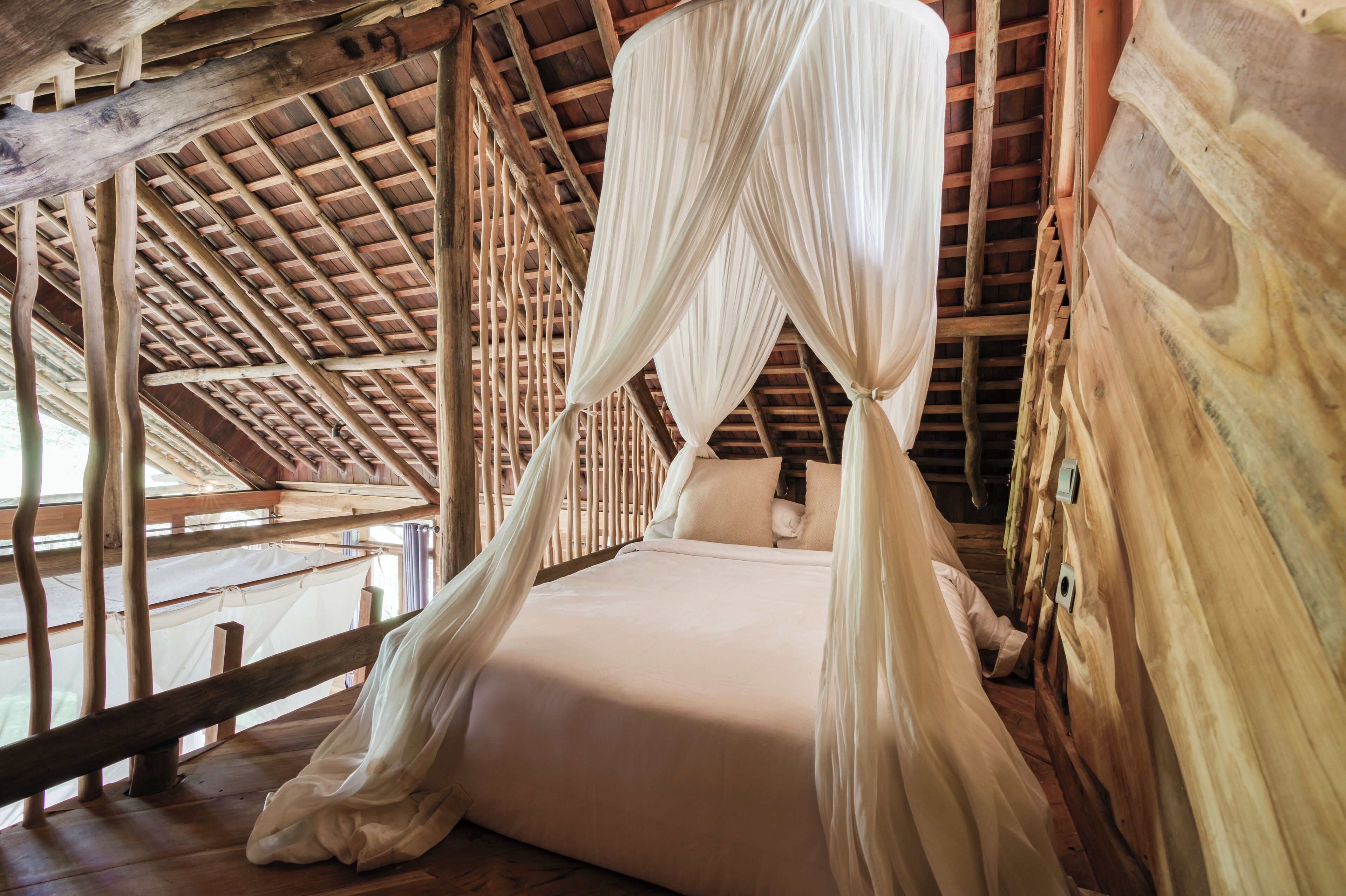 A wooden cabin with a bed under a canopy.