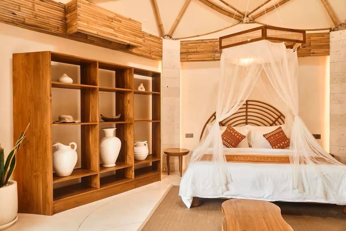 A room with a bed, a wooden cabinet with shelves, and a small round table.