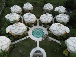 Distribución circular de estructuras abovedadas alrededor de una piscina central, rodeado de vegetación.