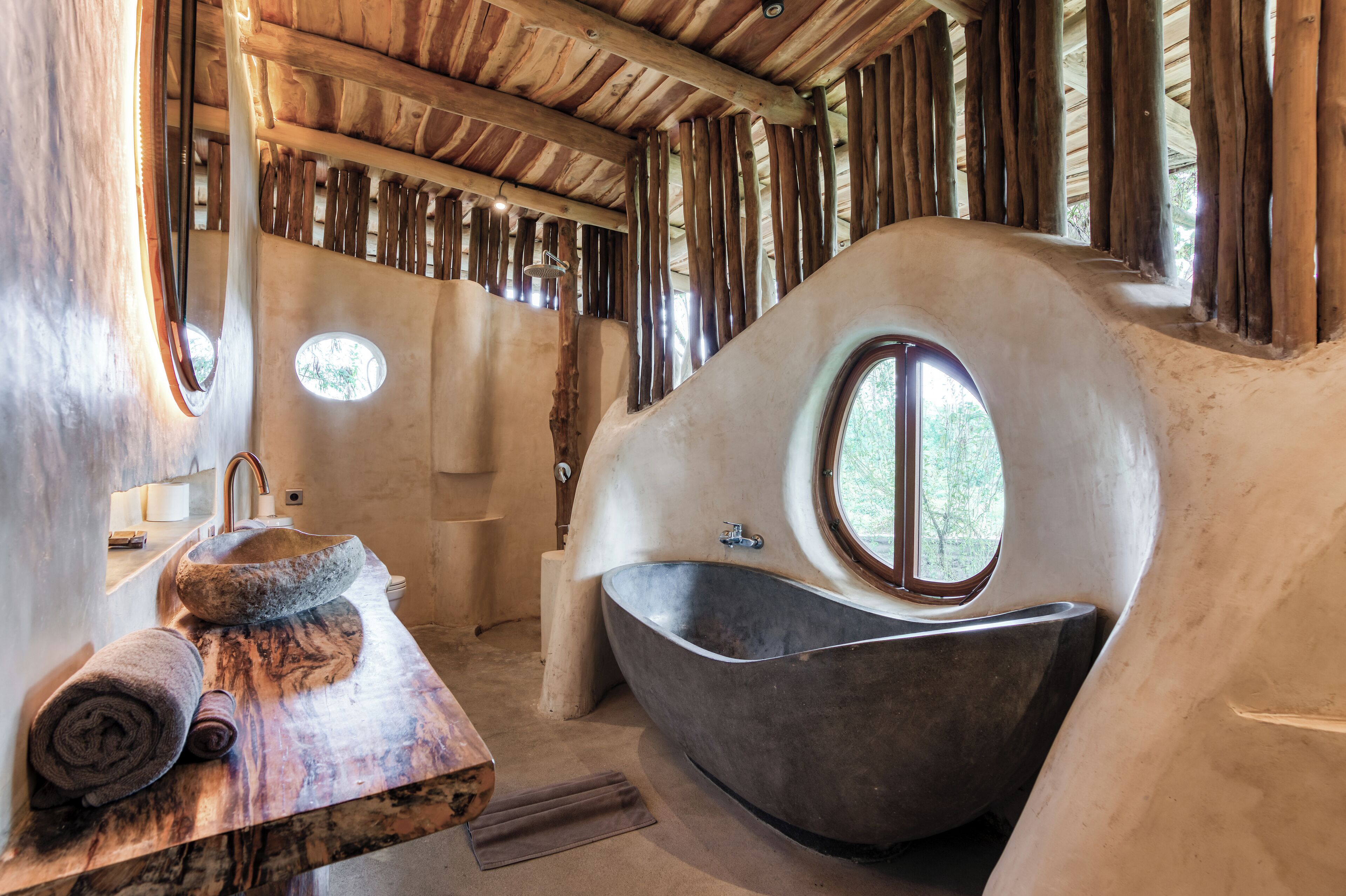 Une salle de bain avec une grande baignoire, un banc en bois et un lavabo.