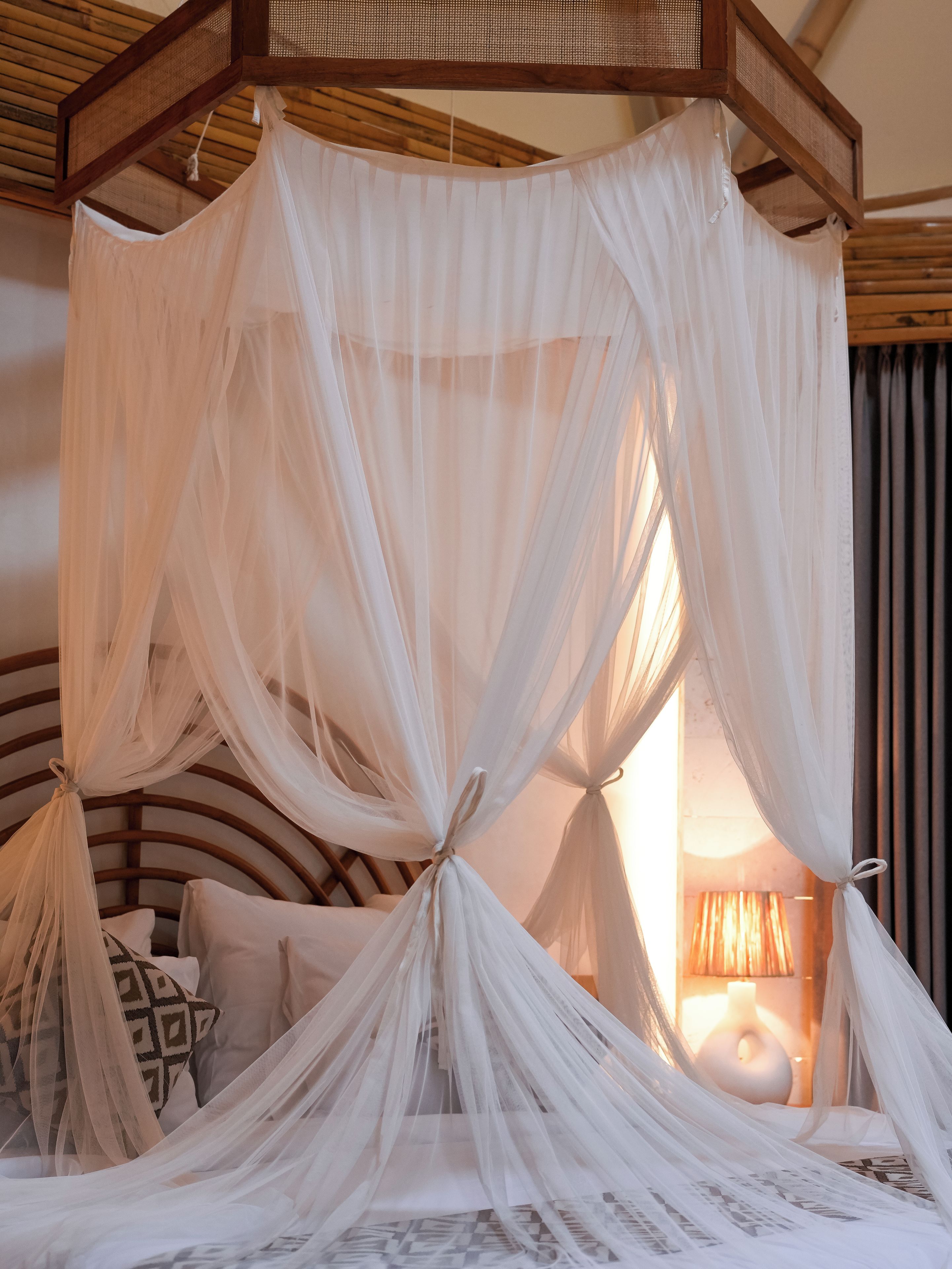 A bed with a canopy, pillows, and a bedside lamp.