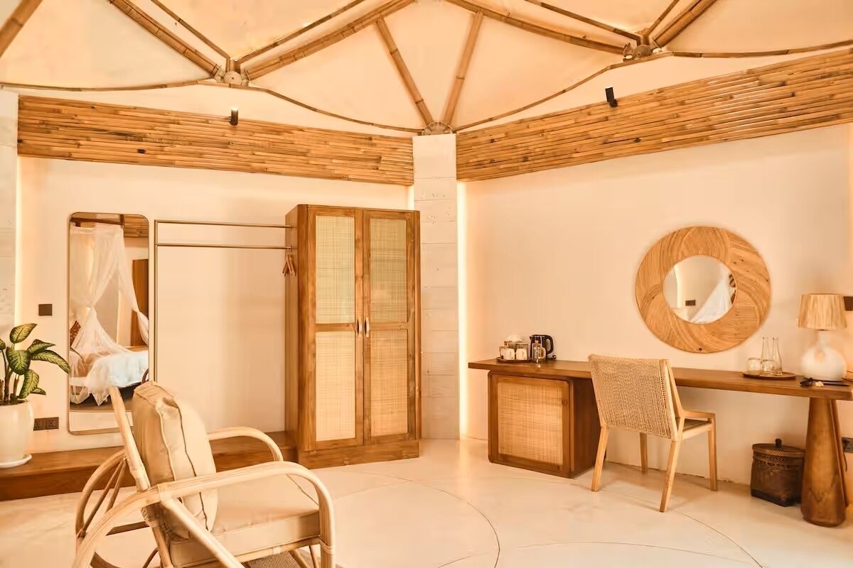 A room with a bamboo ceiling, a bed with a canopy, a desk with a mirror, and wicker furniture.