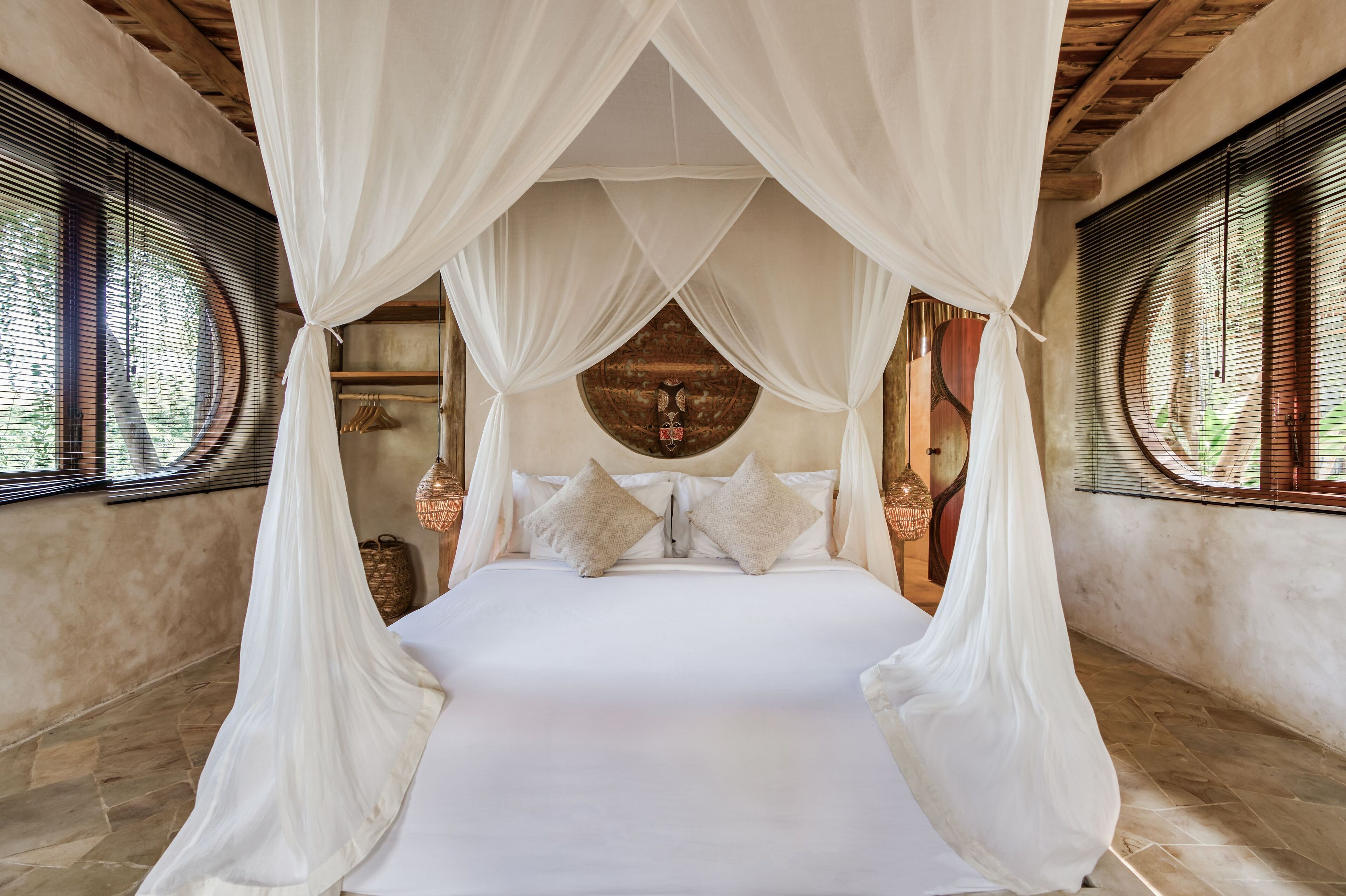 A bed with a canopy, a wooden ceiling, and a wall with a circular design.