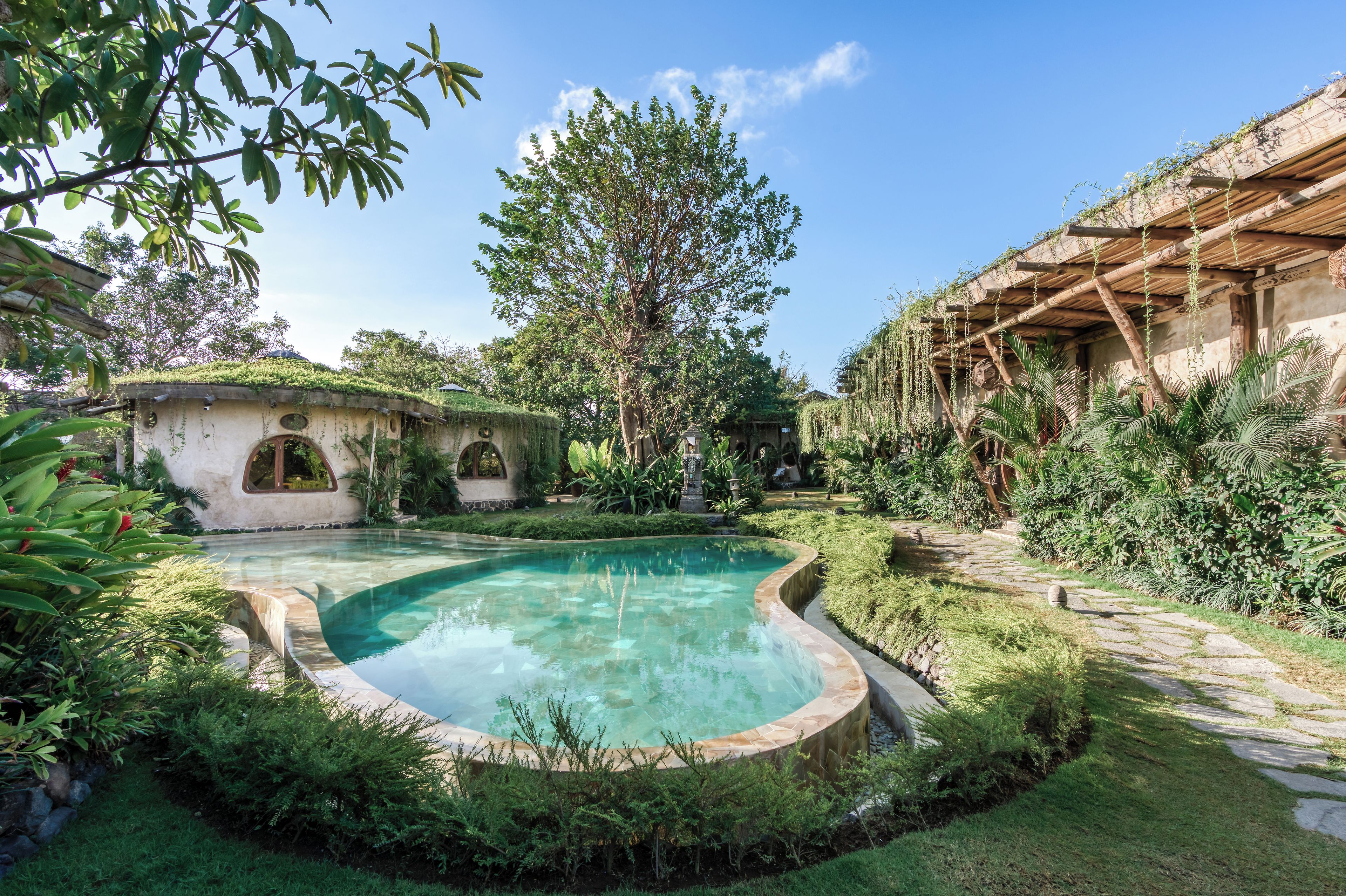 Una piscina rodeada de exuberante vegetación y arquitectura rústica.