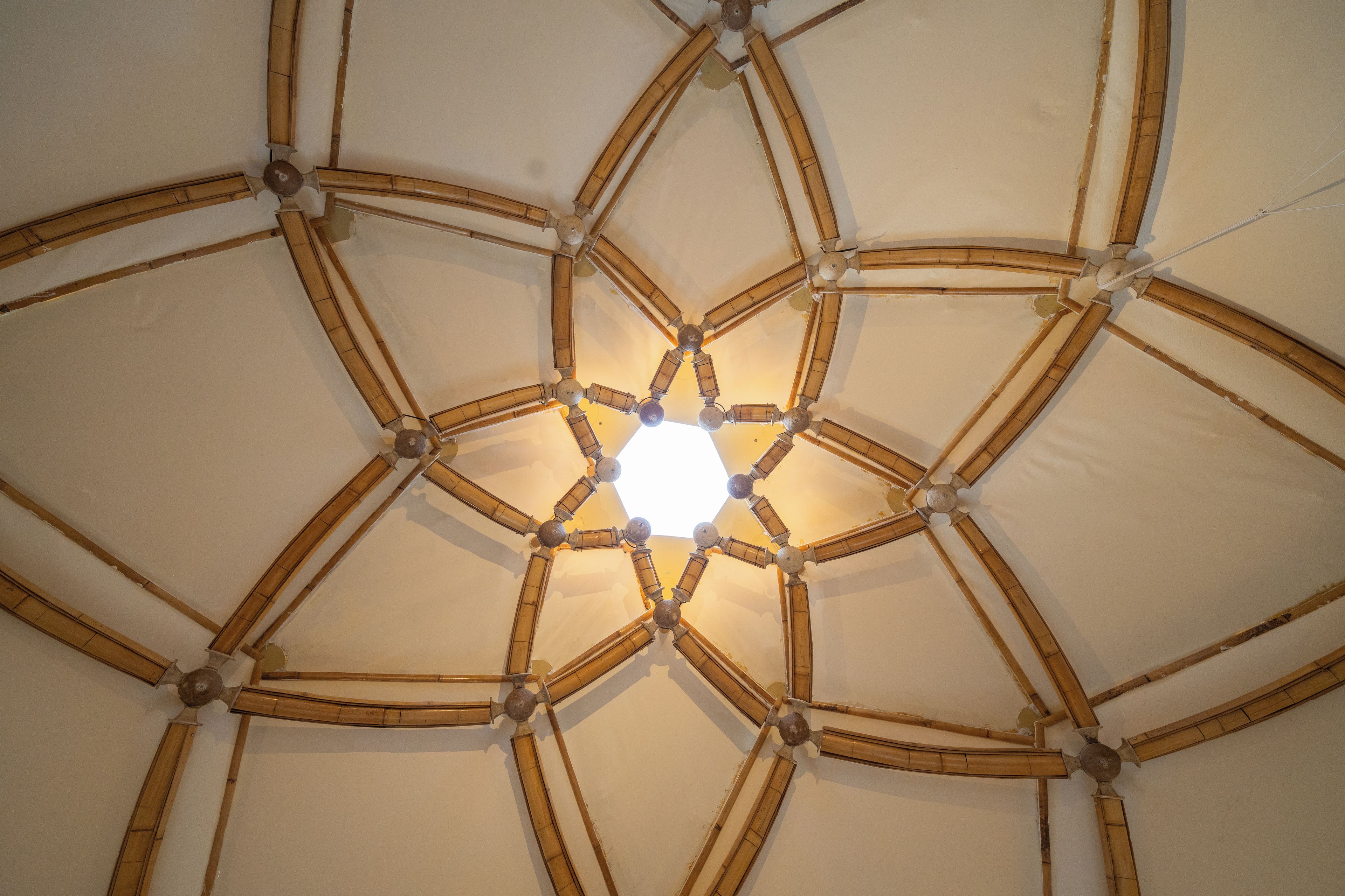 A geometric ceiling design with intersecting wooden beams and a central light fixture.