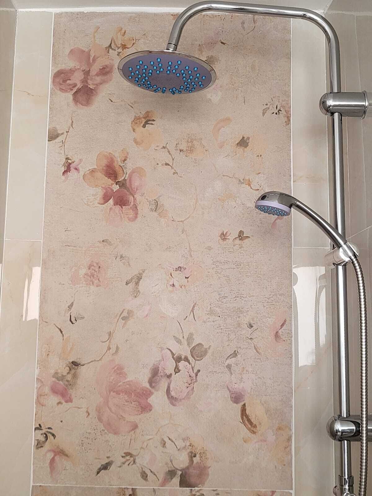 A bathroom with a shower and a floral tile backsplash.