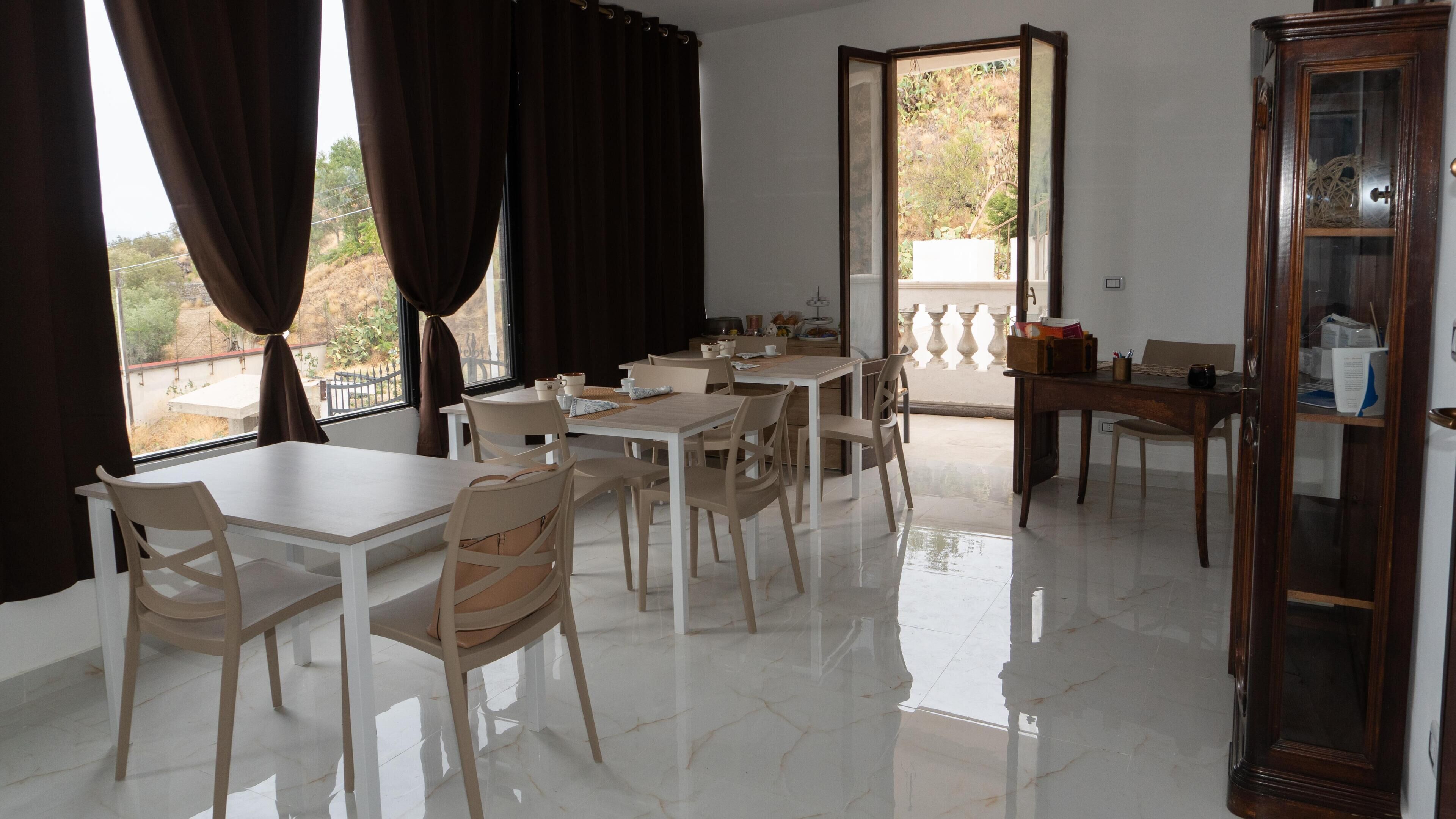 Un comedor con una mesa grande y sillas, un armario de madera y vistas a través de una puerta abierta.