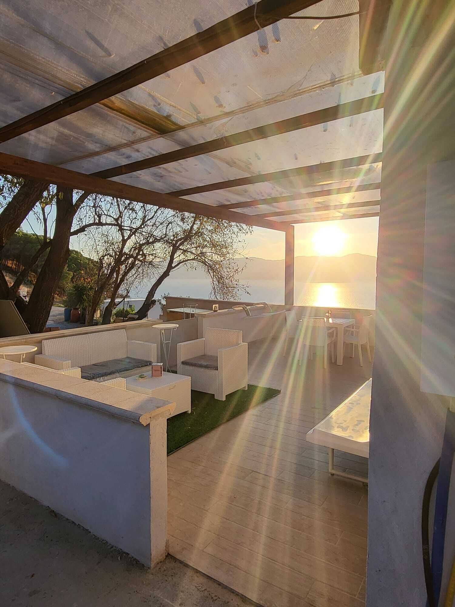 An outdoor patio area with seating arrangements, a view of the sunset, and a covered section with tables and chairs.