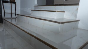 Marmeren trappen met houten leuningen, die naar een hoger verdiep leiden.