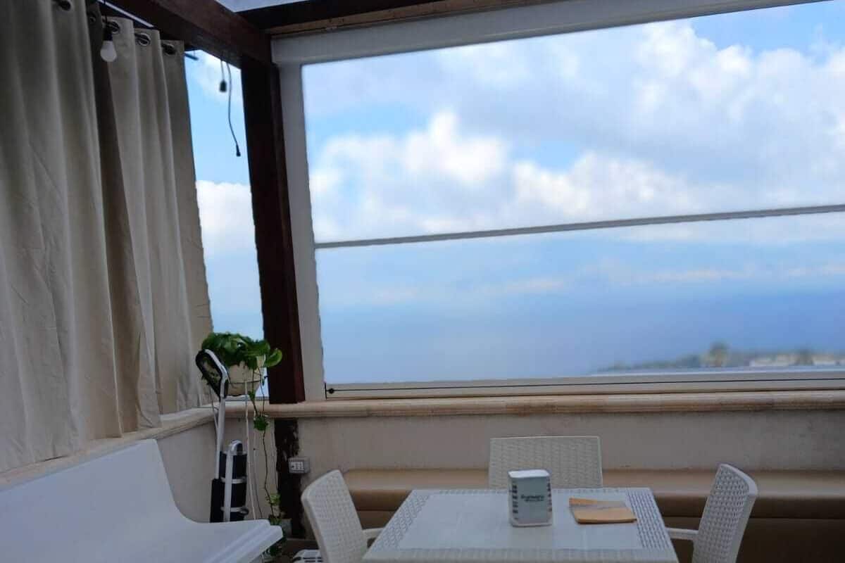 A balcony with a table and chairs, a sofa, and a view of the sea.