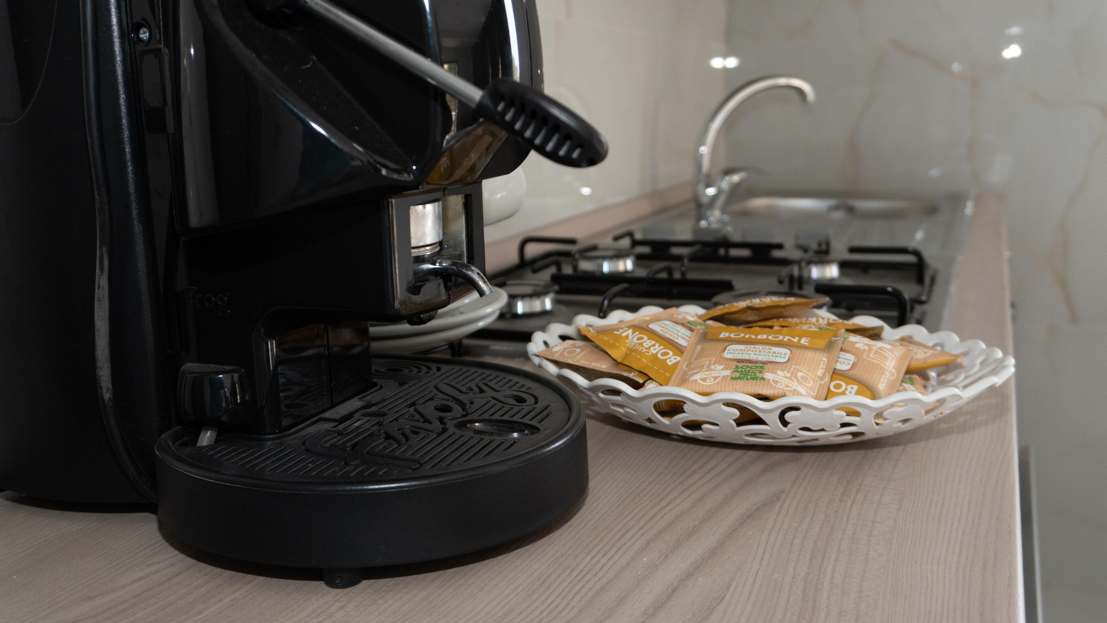 A coffee maker, a basket of biscotti, and a kitchen sink.