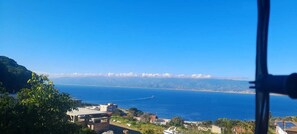 Vista costera con cielo despejado, un barco en el agua y edificios al frente.
