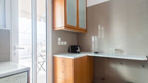 A modern kitchen with wooden cabinets, a white countertop, and a built-in dishwasher. - Neos Kosmos 1Bd Apt with Stunning Views (Athens)