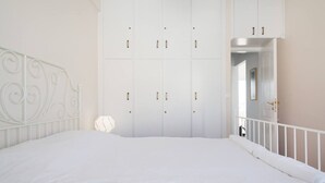 A bedroom with a white bed, a white wardrobe with multiple doors, and a white railing. - Neos Kosmos 1Bd Apt with Stunning Views (Athens)