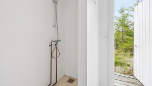 A bathroom with a shower, a toilet, and a sink. There is a window with a view of trees and a wooden deck outside. - Lovely home in Sejerø with WiFi (Sejerø)