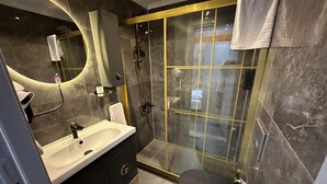 Ein modernes Badezimmer mit einer Duschkabine, einer schwarzen Toilette und einem Waschtisch mit Spiegel.