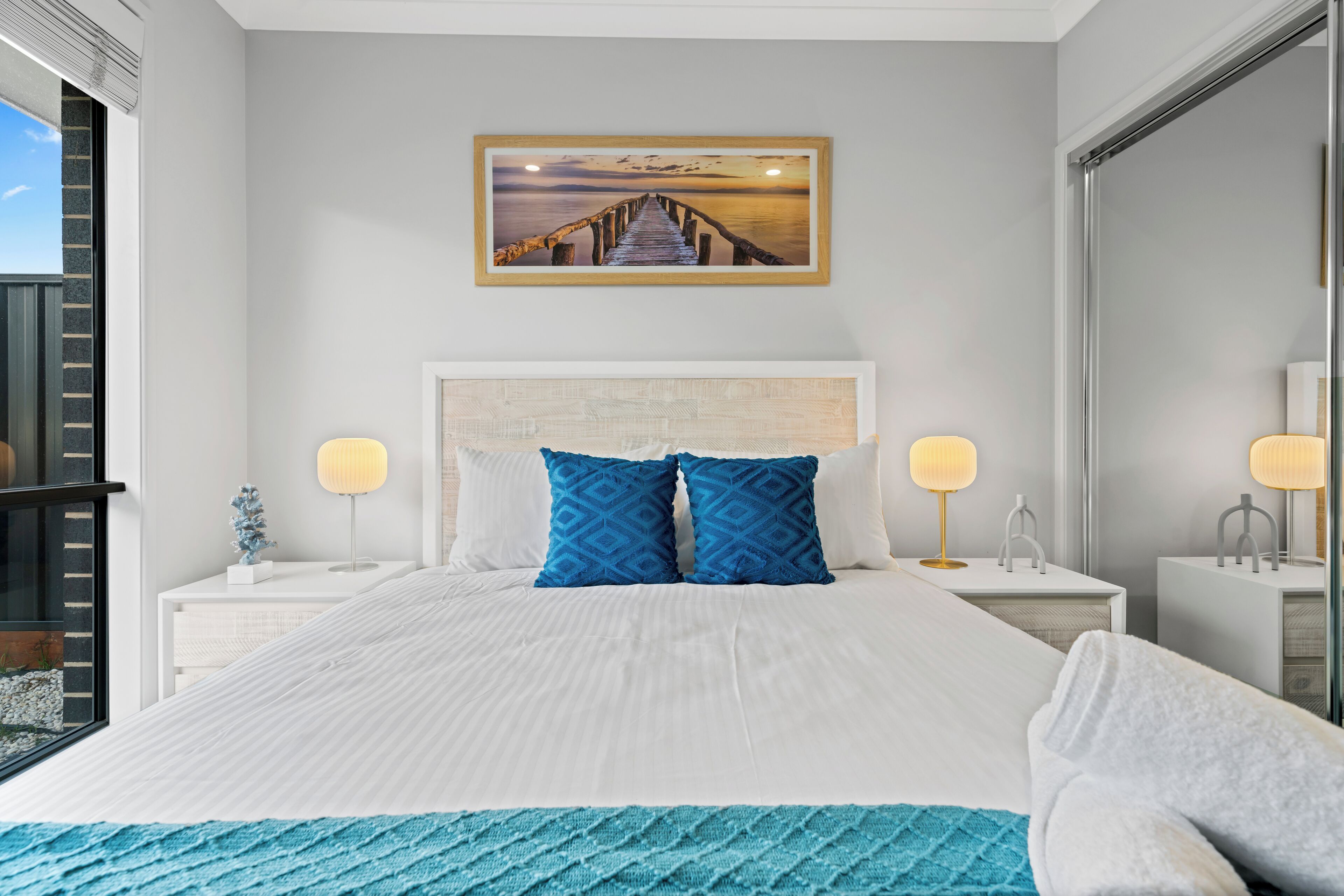 Camera d'albergo ordinata con un letto grande, due comodini con lampade, un quadro appeso al muro e vista dalla finestra.