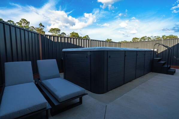 Un área de hidromasaje al aire libre con sillones de descanso y una escalera que conduce a una terraza.