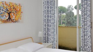 Une chambre à coucher avec un lit, une table de chevet, une lampe et une fenêtre avec des rideaux.