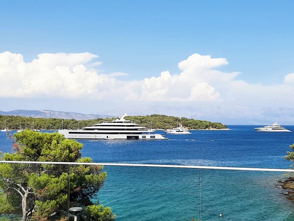A marina with several yachts docked, surrounded by clear blue waters and a mountainous backdrop.