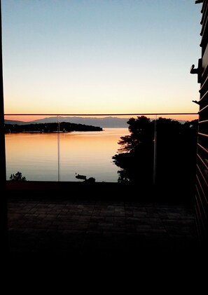 A view of a calm lake at sunset with a distant mountain range.