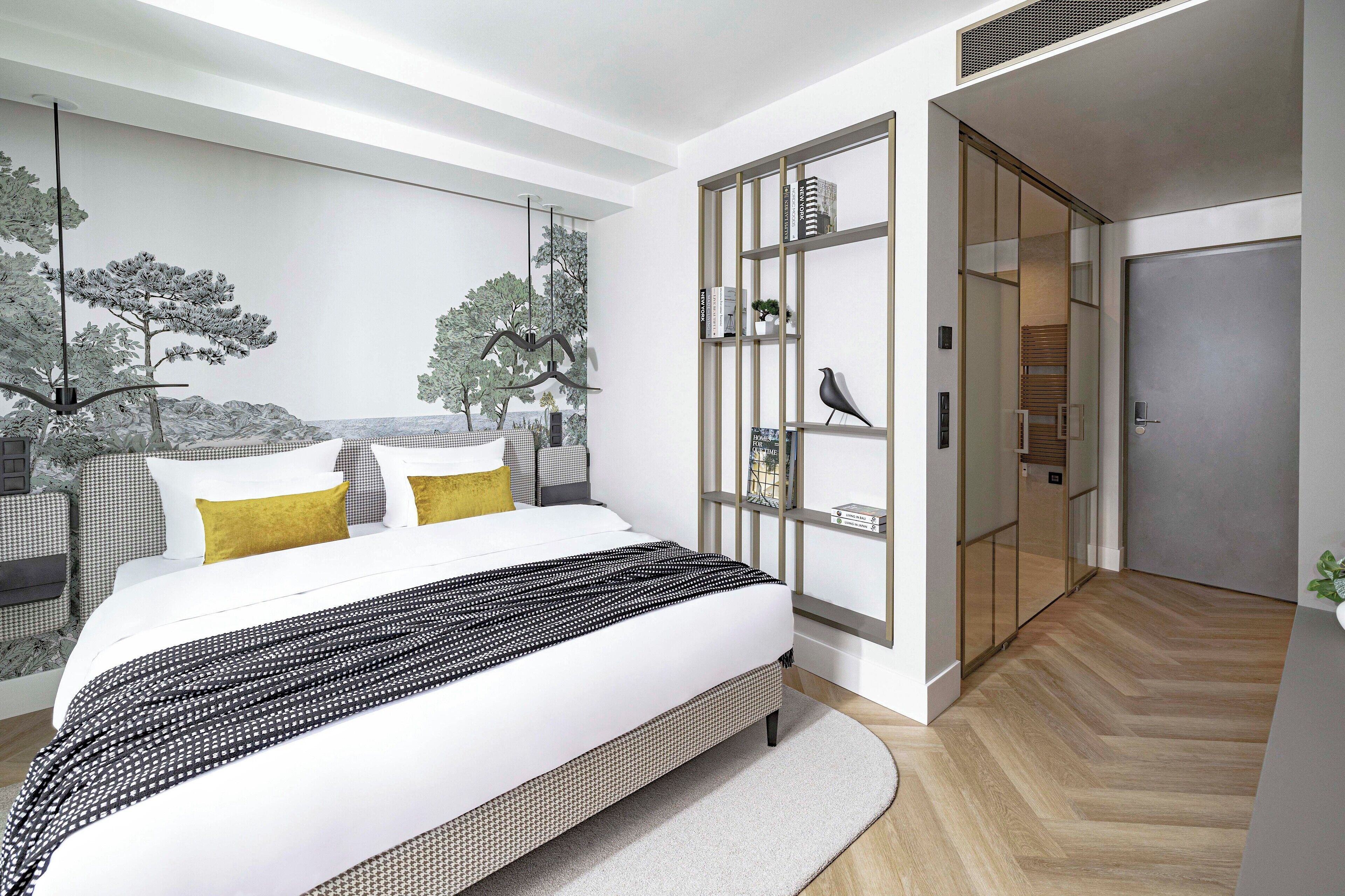 Ein modernes Schlafzimmer mit einem großen Bett, einem eingebauten Kleiderschrank und einer Wandmalerei von Bäumen.