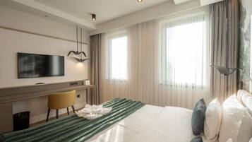 A modern hotel room with a bed, a desk, a chair, and a television.