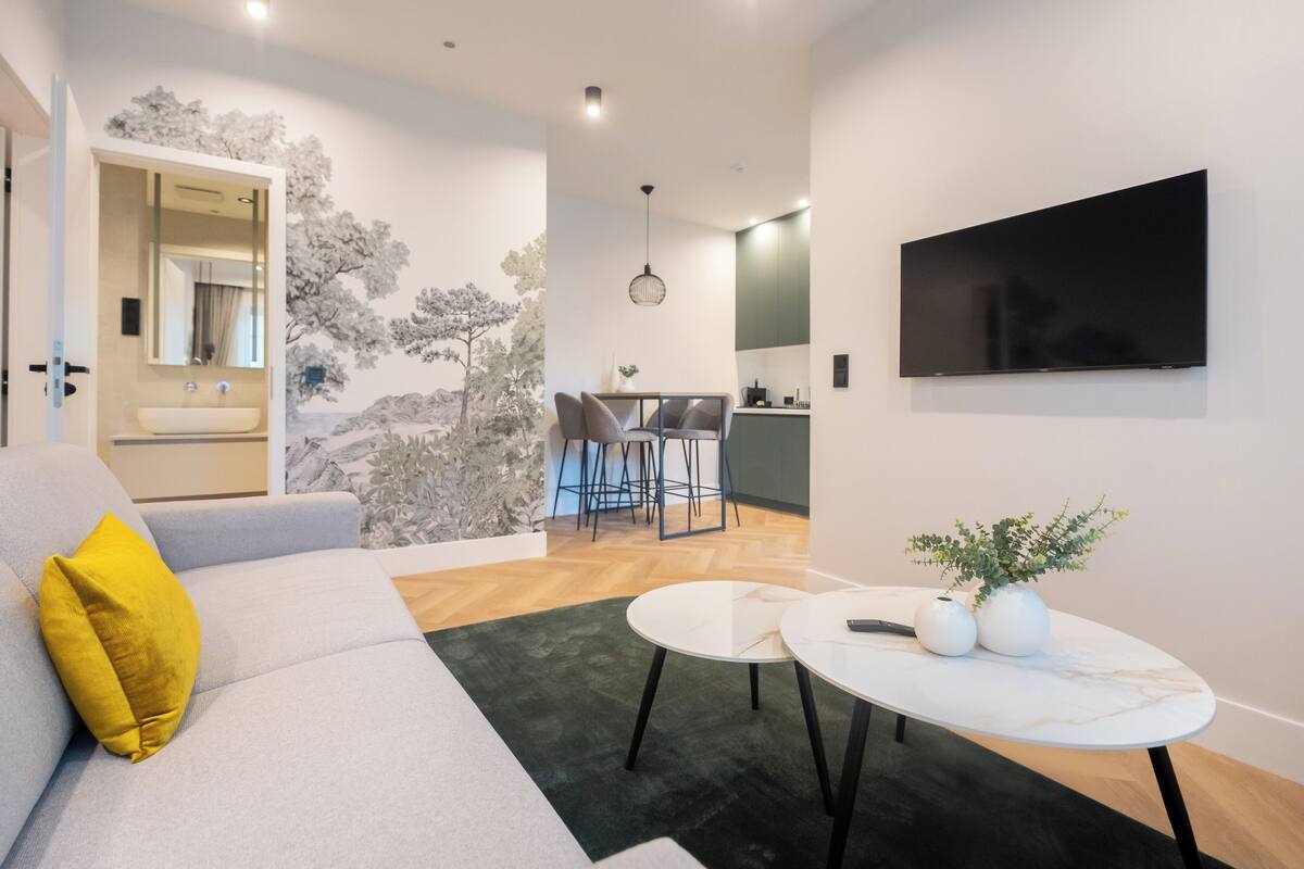 A modern living room with a sofa, a coffee table, and a TV mounted on the wall.
