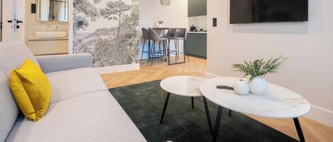 Una sala de estar moderna con un sofá, una mesa de centro y un televisor montado en la pared.