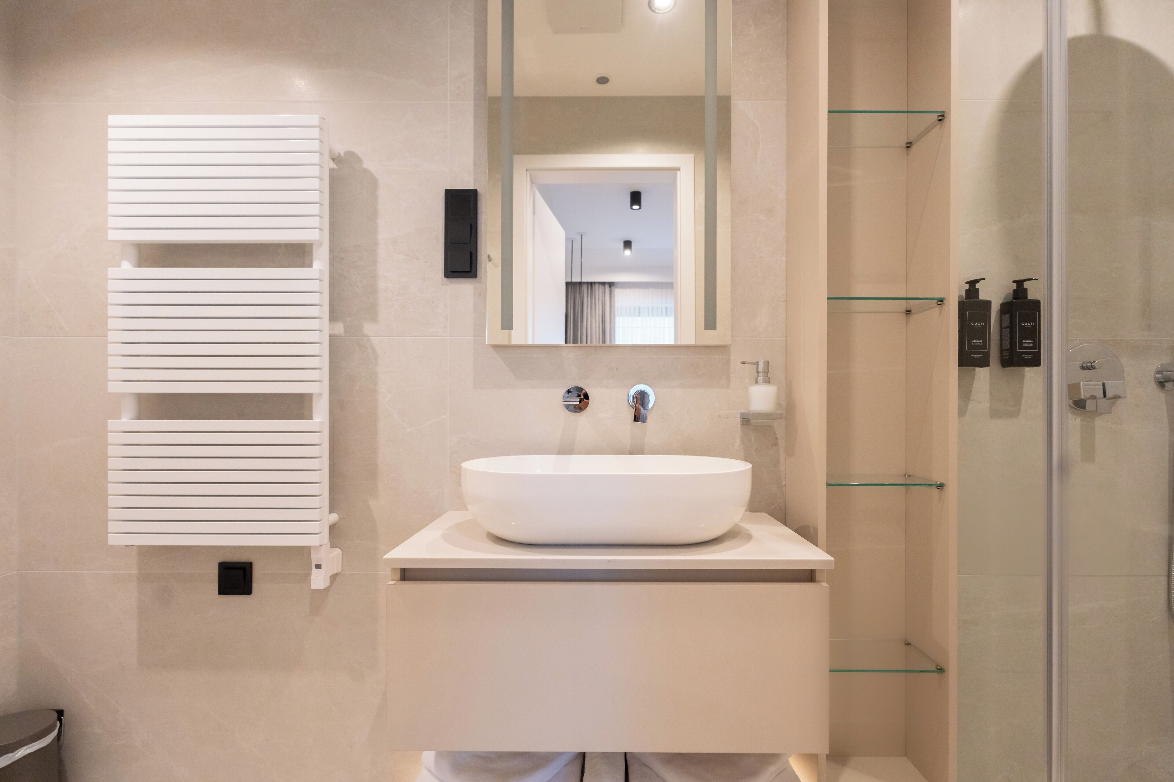A modern bathroom with a large white sink, a mirror above it, and a glass shower enclosure.