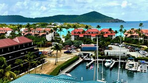 Un puerto deportivo con barcos amarrados, una zona de estacionamiento y edificios con tejados rojos.