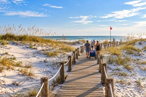 A wooden boardwalk leading to a beach with sand dunes and a flag.