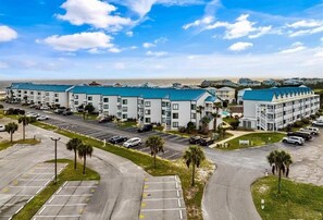 A hotel with multiple buildings, a parking lot, and a view of the beach. - Surf's Up Beachfront Resort Studio | Pools + Beach Access (Gulf Shores)