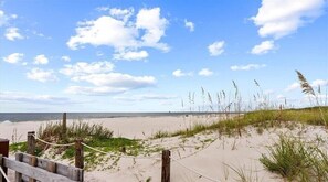 A sandy beach with a wooden fence and rope barrier. - Surf's Up Beachfront Resort Studio | Pools + Beach Access (Gulf Shores)