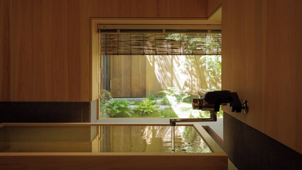 A wooden room with a large window, a bathtub, and a faucet. - RYOKAN KURASHIKI Residence (Kurashiki)