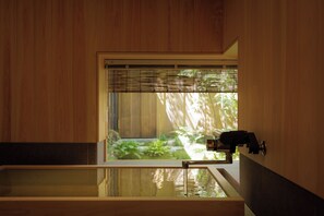 Een houten kamer met een groot raam, een badkuip en een waterkraan.