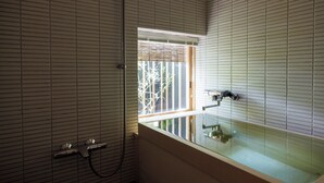 A bathroom with a bathtub, a window, and a shower area. - RYOKAN KURASHIKI Residence (Kurashiki)