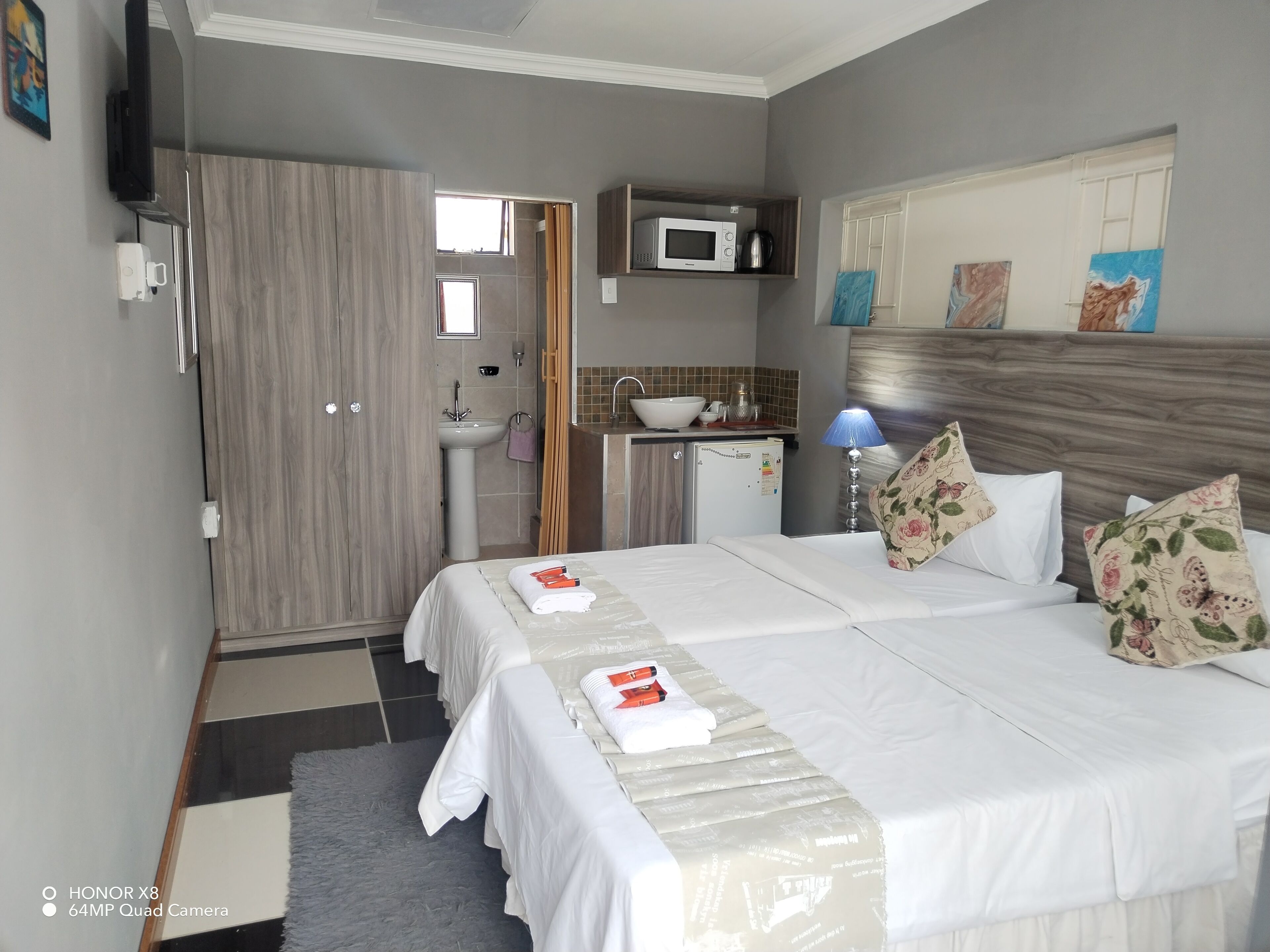A hotel room with a bed, bedside tables, a sink, a microwave, and a wardrobe.