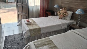A hotel room with two beds, a large window, and a view of the street outside. - Room-home of Peace and Tranquility (Pretoria)
