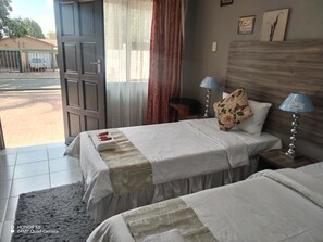 A hotel room with two beds, a large window, and a view of the street outside. - Room-home of Peace and Tranquility (Pretoria)