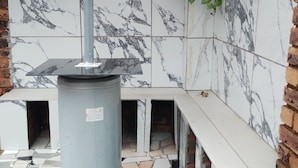 A bathroom with marble tiles, a metal column, and a bench. - Room-home of Peace and Tranquility (Pretoria)