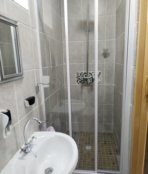 A bathroom with a white sink, a glass-enclosed shower, and a mirror on the wall. - Room-home of Peace and Tranquility (Pretoria)